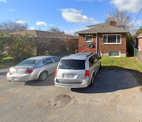 two cars parked in a parking lot in front of a house